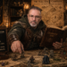 Frank Jamison dressed in medieval fantasy attire studies a tabletop role playing game map while moving a miniature figure, holding an open campaign log book, surrounded by dice, candles, and a chalkboard labeled inventory system in a richly detailed Dungeons and Dragons setting.